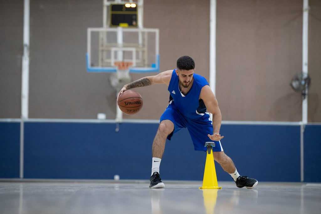 A basketballer practising his skills using a cone