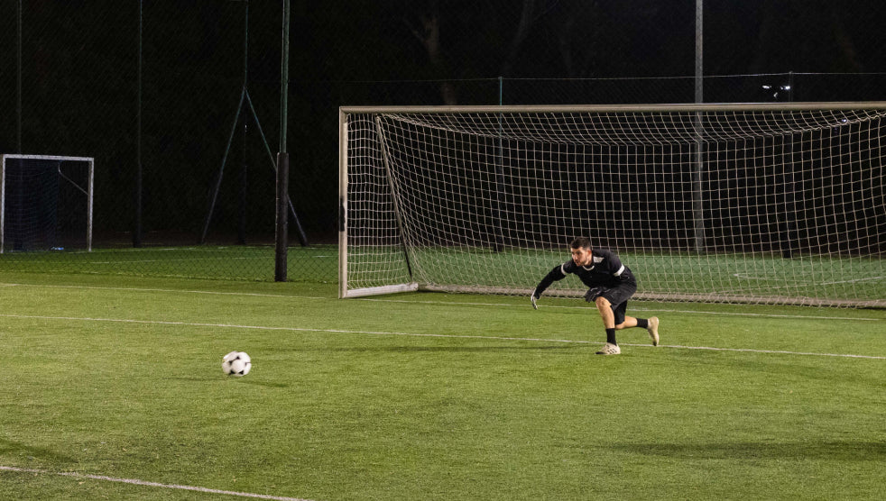 A goalkeeper running to defend the goal post from an incoming ball