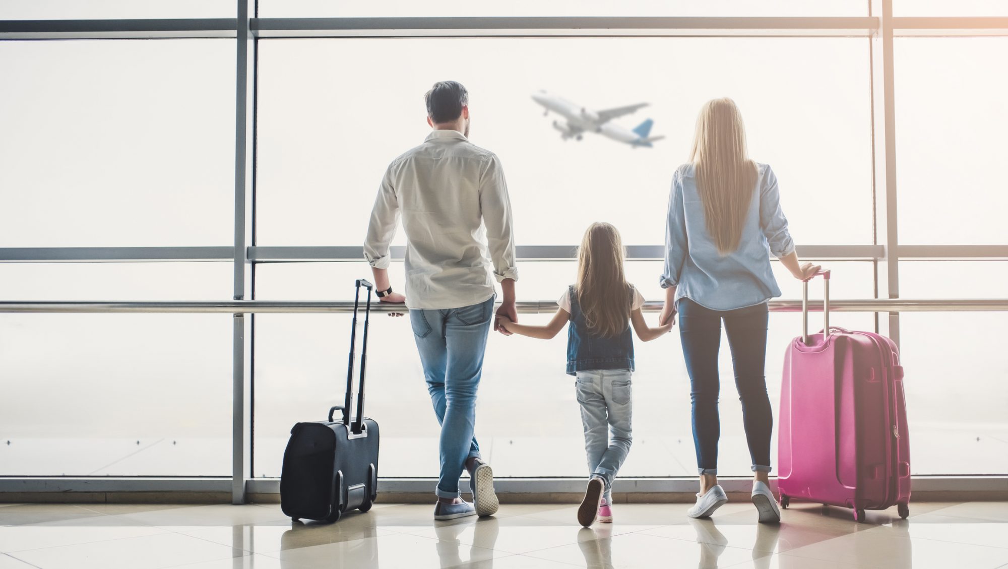 Family in airport. Attractive young woman, handsome man and their cute little daughter are ready for traveling! Happy family concept.