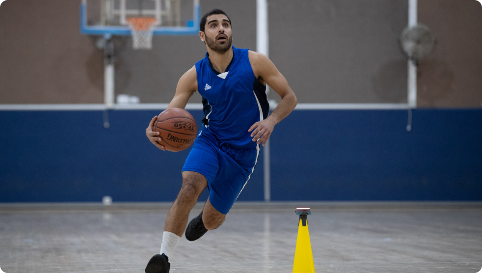 A basketballer dribbling around a Pod and cone