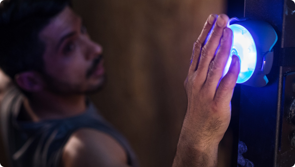 A man tapping a BlazePod Pod strapped to a wall