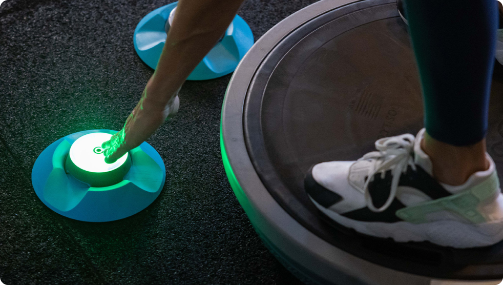 Someone balancing on a Bosu ball trying to tap out a BlazePod Pod